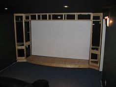 an empty theater room with black walls and wooden shelves on either side of the screen