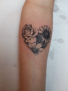 a heart shaped tattoo with flowers on the arm