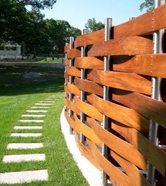 a wooden fence in the middle of a grassy area with stepping stones on each side