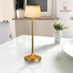 a table lamp sitting on top of a white counter next to a potted plant