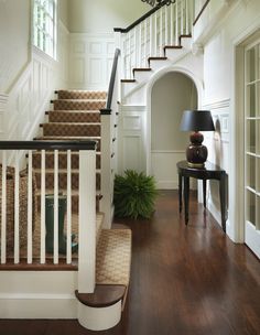 an entryway with stairs, table and lamp