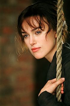 a woman holding onto a rope with one hand and looking at the camera while wearing a black shirt