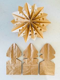 two brown paper bags are next to an origami star on a white wall