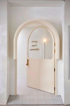 an arched doorway leading into a bathroom with white tile flooring and walls that have gold lettering on it