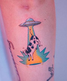 a cow with an alien flying saucer on its head is shown in this tattoo