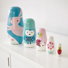 five colorful nesting dolls sitting on top of a white counter