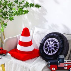 a red and white car is parked next to a toy firetruck, with a traffic cone on top