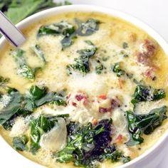 a bowl of soup with spinach, cheese and other toppings on the side