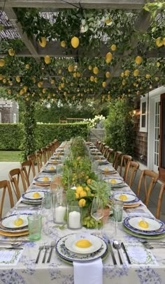 an outdoor dining area with lemons hanging from the ceiling and place settings on the table