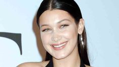 a close up of a person wearing a black dress and smiling at the camera with her hair pulled back