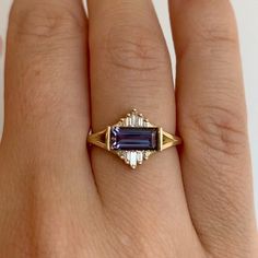 a woman's hand wearing a gold ring with an amethorate and diamond