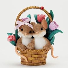 two little mice sitting in a basket with flowers on it's side and one is kissing the other