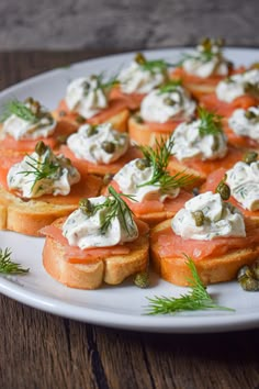 a white plate topped with toasted bread covered in cream cheese and salmon