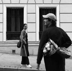 black and white photograph of two people walking down the street, one holding a bag