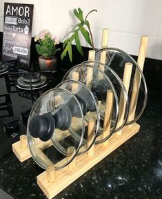 a set of four glass dishes sitting on top of a wooden rack next to a potted plant