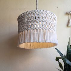 a white chandelier hanging from the ceiling next to a potted plant in a room