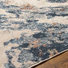 an area rug with blue and orange flowers on it, sitting on a wooden floor