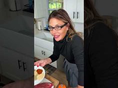 a woman in black shirt and glasses preparing food