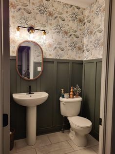 a white toilet sitting next to a sink in a bathroom under a large round mirror