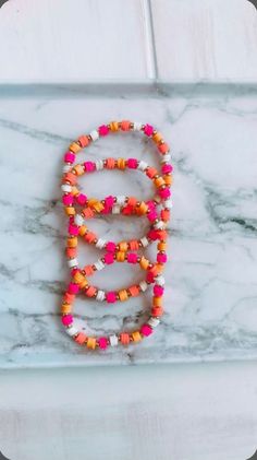 the letter b is made out of colorful beads on a marble surface with a white background