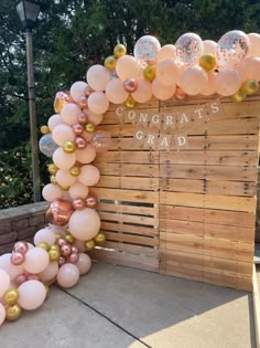 balloons are arranged around the entrance to an outdoor graduation party with pink, gold and white balloons