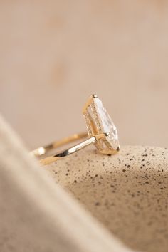 a diamond ring sitting on top of a white stone bowl with black speckles