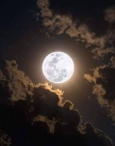 the full moon is shining brightly in the night sky with fluffy clouds and dark blue skies