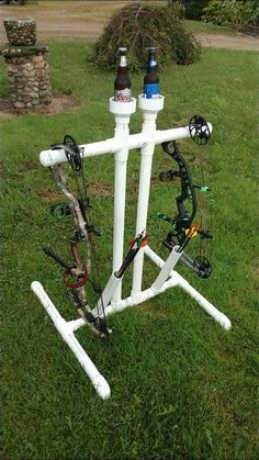 a white bicycle rack with two bottles on top of it in the middle of some grass