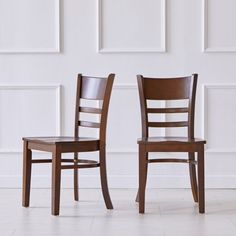 two wooden chairs side by side against a white wall