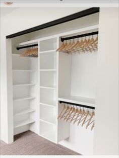 an open closet with white shelves and wooden hangers