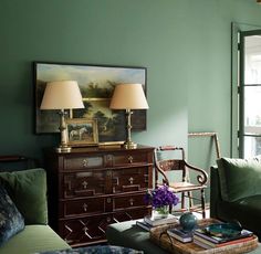 a living room with green walls and two lamps on top of the tables in front of them