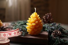 a candle that is sitting on top of a wooden table next to pine cones and other decorations