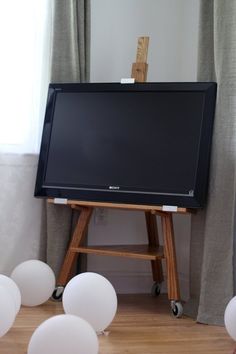 an easel with white balloons in front of it and a black board on the floor