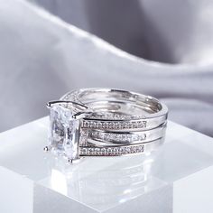 an engagement ring and wedding band set with a princess cut diamond in the center on a white surface