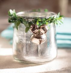 a glass jar filled with metal bells and greenery