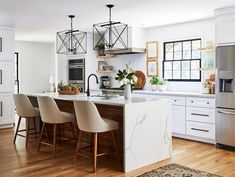 a kitchen with white cabinets and marble counter tops is pictured in this image, there are four chairs at the island