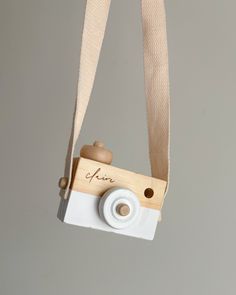 a small wooden camera hanging from a white string with the word love written on it