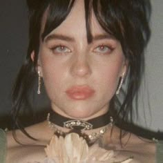 a close up of a person wearing a choker and holding a flower in her hand