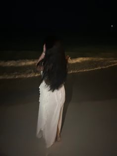 a woman standing on the beach at night