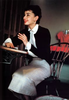 a woman sitting in a chair with her arms crossed and looking off to the side