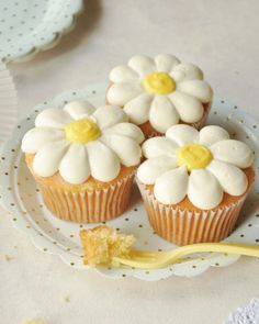 three cupcakes with white frosting and yellow centers on a polka dot plate