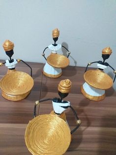 four small gold and white vases sitting on top of a wooden table next to each other