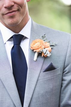 a man in a gray suit with an orange boutonniere on his lapel