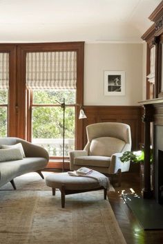 a living room filled with furniture and a fire place in front of two large windows