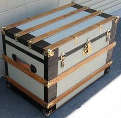 an old trunk is sitting outside on the ground next to a wall with a door