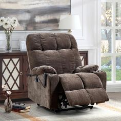 a brown recliner sitting in a living room next to a table with flowers on it