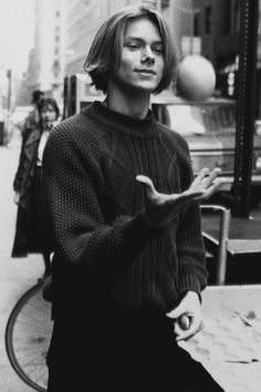 black and white photograph of a woman standing on the sidewalk with her hands out in front of her