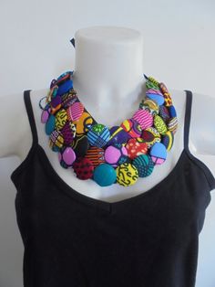 a woman wearing a black tank top and multi colored beads on her necklace, standing next to a white mannequin