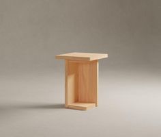 a small wooden table sitting on top of a white floor next to a gray wall