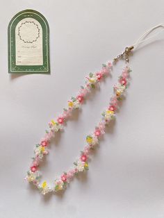 the necklace is decorated with multicolored flowers and beads, along with a tag